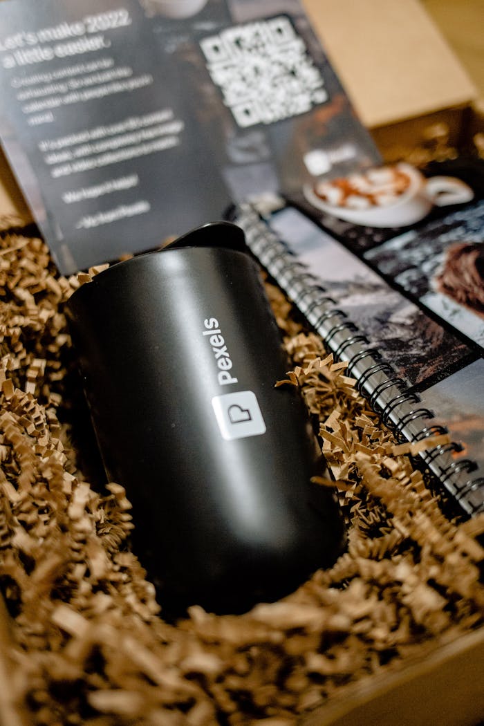 Close-up of a Pexels-branded mug and notepad in a gift box, ideal for corporate gifting.