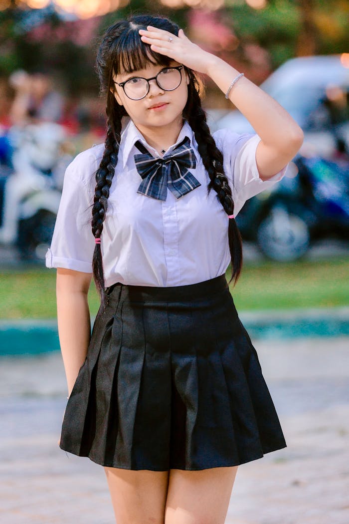 Teen girl wearing school uniform and glasses on a sunny day.